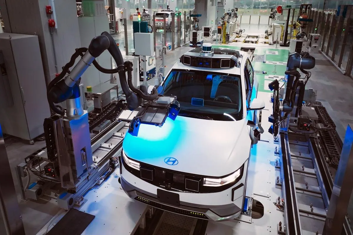 A view inside a Tesla factory showing a Cybertruck on the assembly line with workers in the background