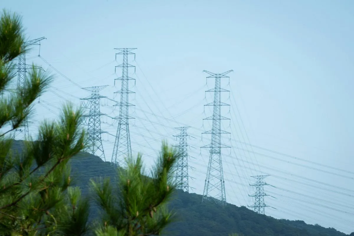 A high-voltage electricity transmission substation with power lines and transformers under a cloudy sky.