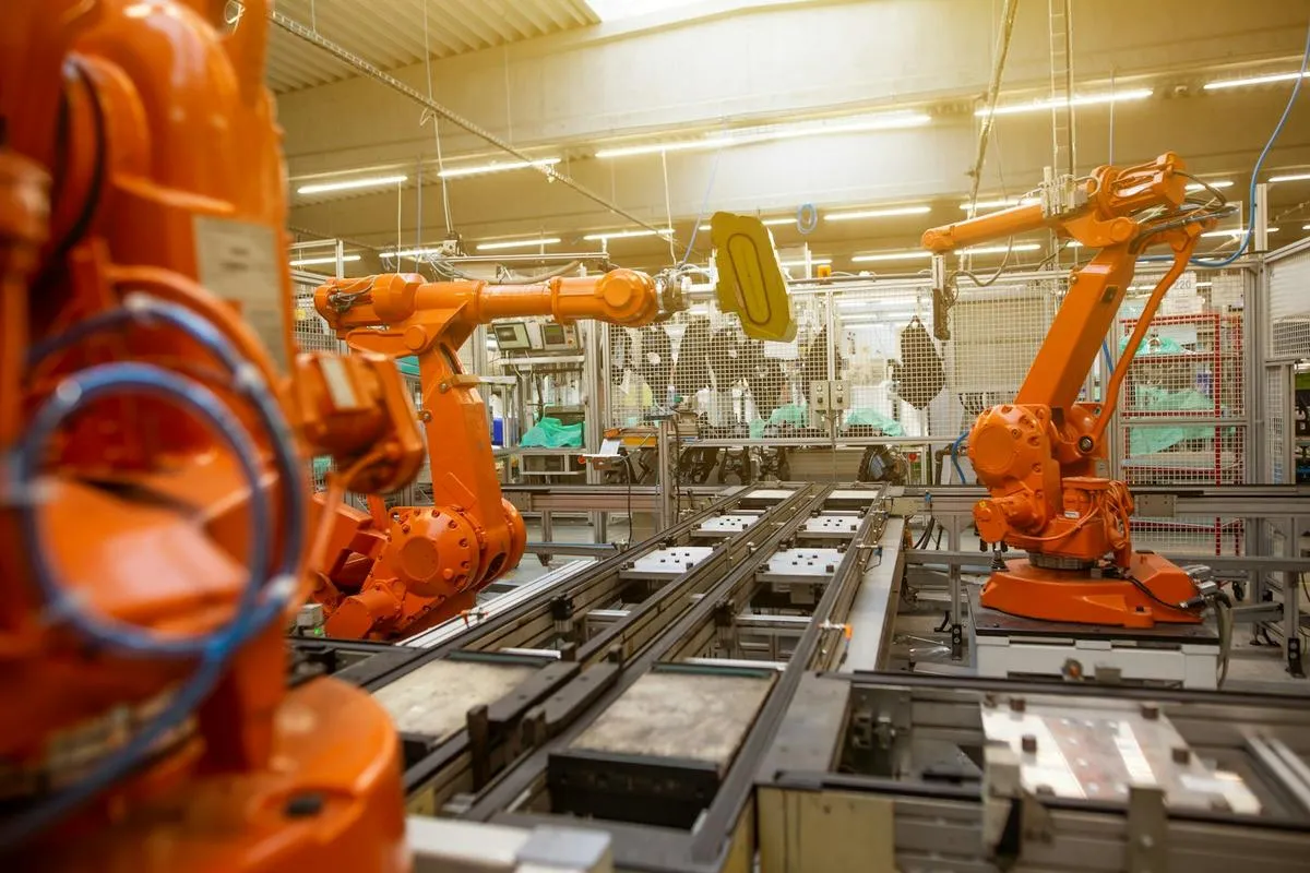 Workers on a factory floor with robotic arms.
